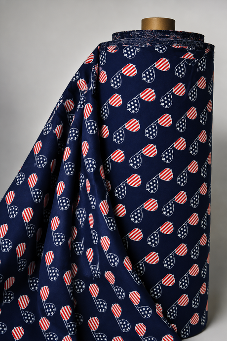 A roll of navy blue fabric draped over a wooden mannequin stand, featuring a repeating pattern of red and white striped heart-shaped sunglasses with white star details.