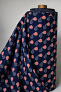 A roll of navy blue fabric draped over a wooden mannequin stand, featuring a repeating pattern of red and white striped heart-shaped sunglasses with white star details.